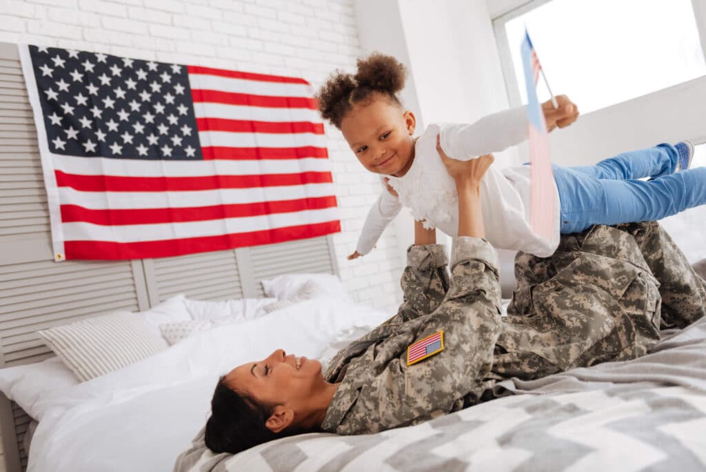 A member of the armed forces plays with her daughter.